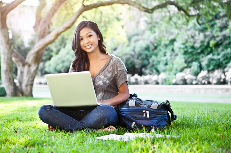 Picture of student on campus outside with laptop