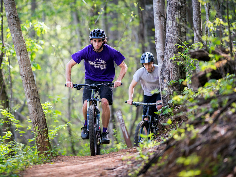 students riding bicycles on the campus trail