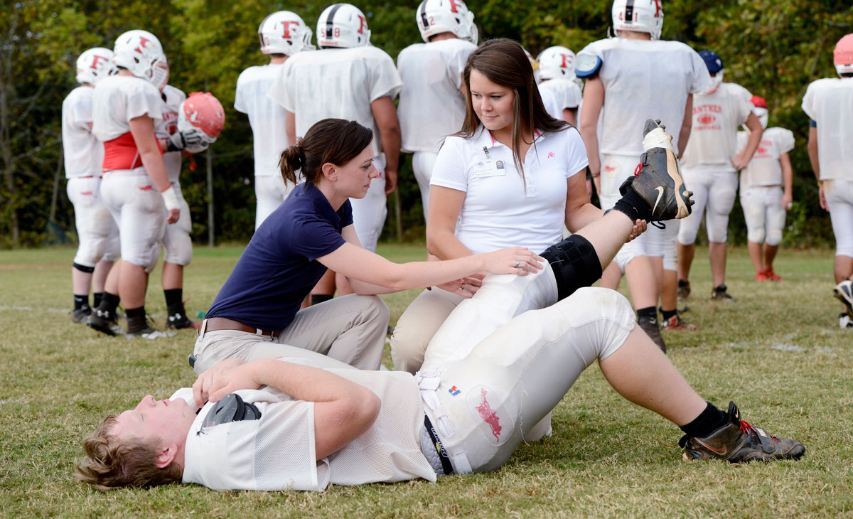 Athletic trainers carry out a field evaluation on a football player