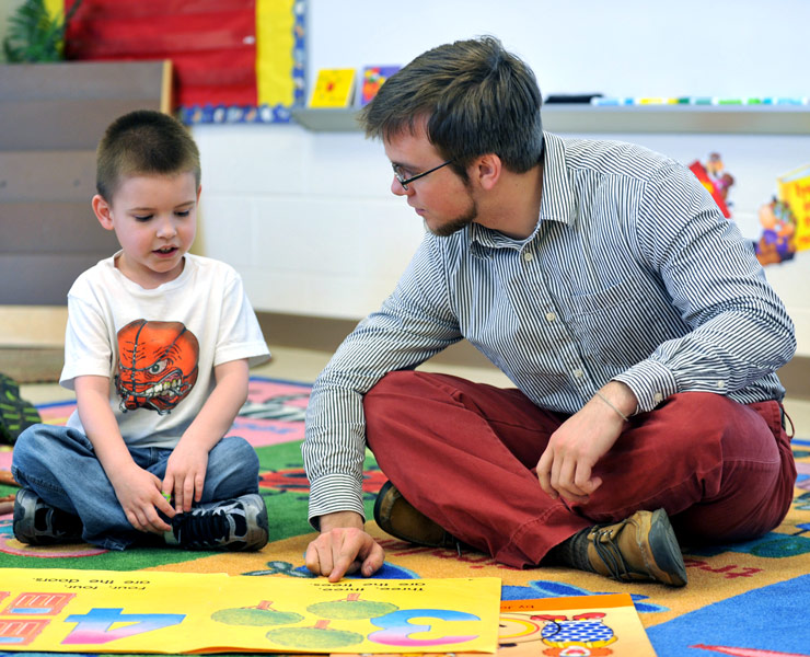 Elementary student teacher reading with a student