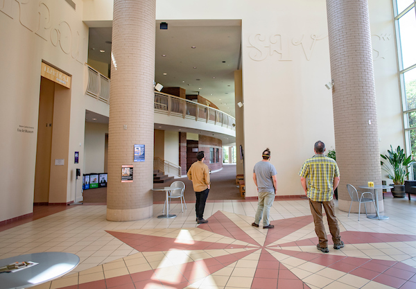 Bardo Arts Center Star Atrium with three individuals looking at the Cherokee Syllabary without translation