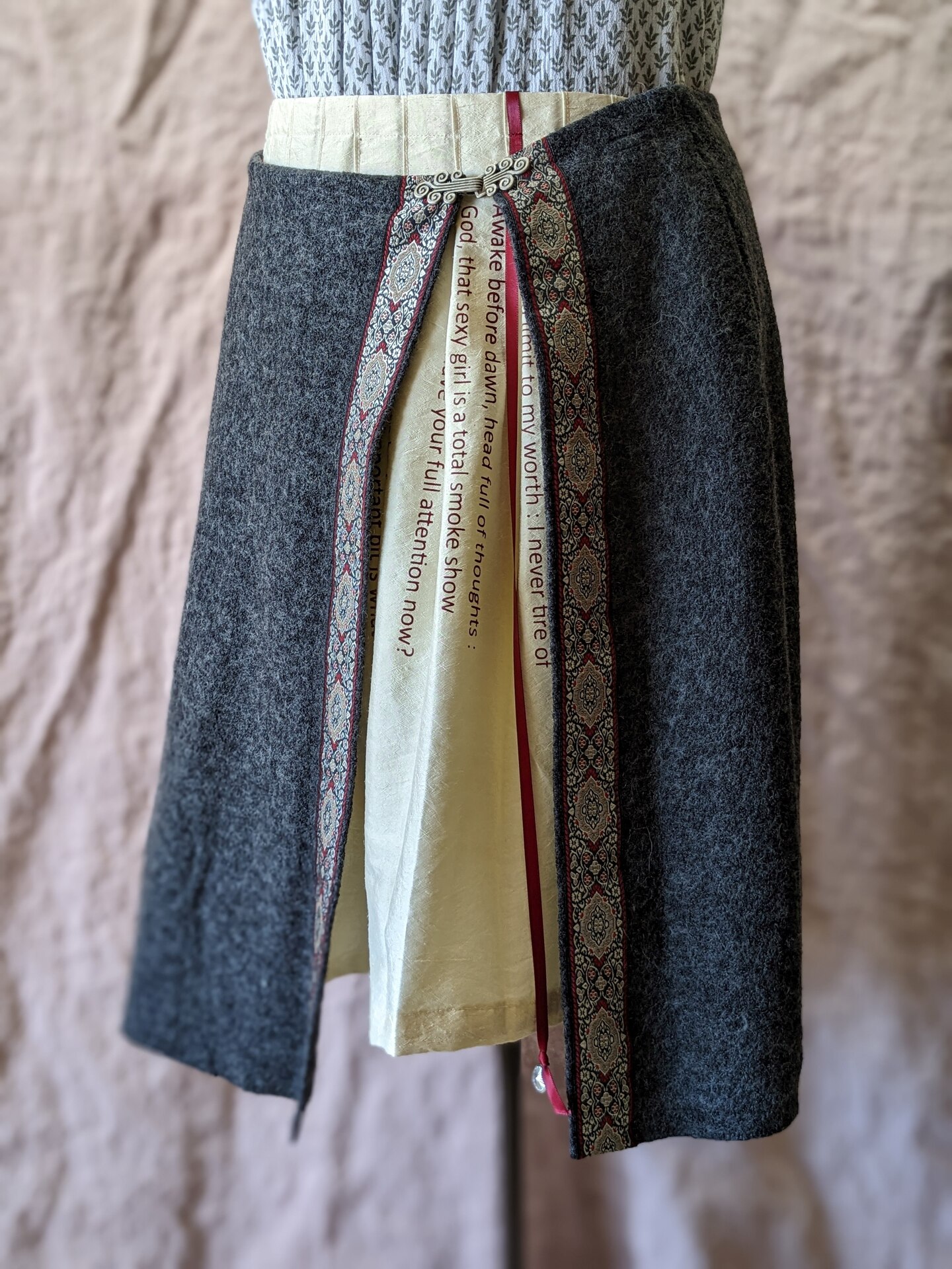 a woolen skirt with a red ribbon on the hem with an underlayer that has a quote on the skirt. 