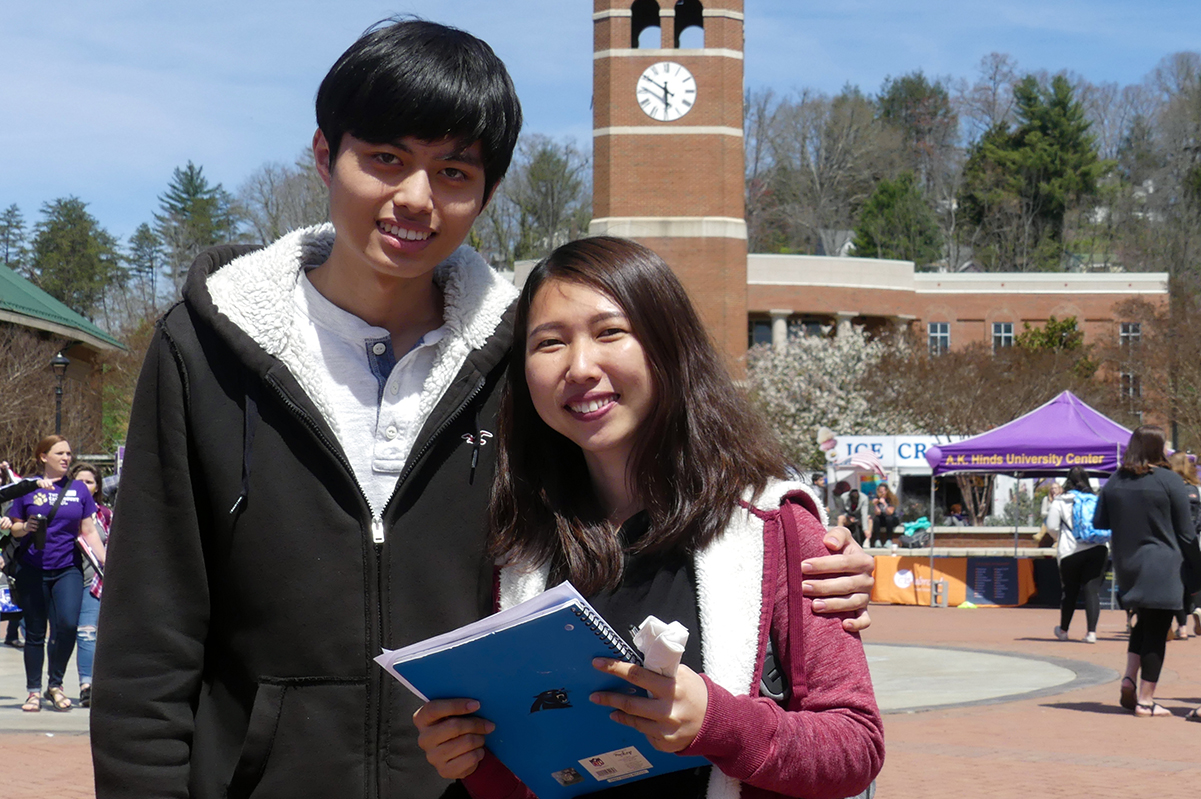 In-Person Programs button - International student in front of WCU's alumni tower