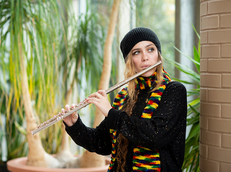 studnet playing the flute in an atrium