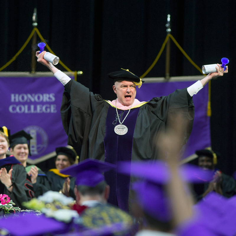 Dr. Belcher blowing airhorns at a WCU Commencement ceremony