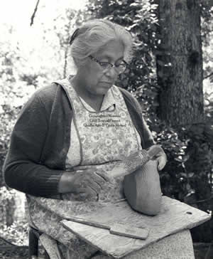 Cora Wahnetah at work with a carved paddle
